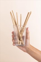 Close up hand holding glass with straws