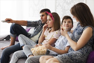 Family eating popcorn while watching television home