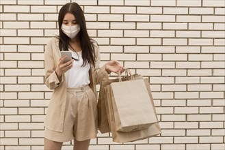 Woman holding shopping bags wearing mask front view