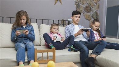 Boys playing video games girls using smartphones