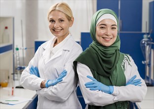Front view smiley female scientists lab posing with arms crossed