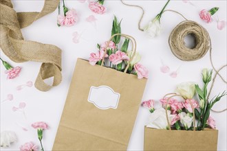 Jute ribbon spool thread paper shopping bags with eustoma carnations flowers white background