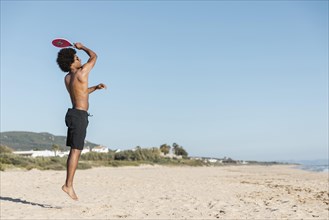 Man jumping with tennis racket beach