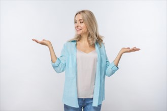 Smiling young woman shrugging isolated against white background