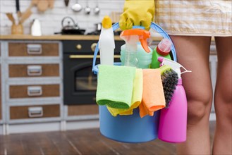Female janitor holding cleaning accessories bucket standing kitchen