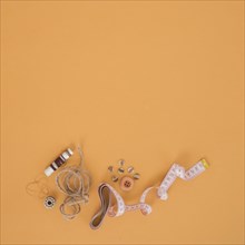 Brown spool string buttons measuring tape orange backdrop