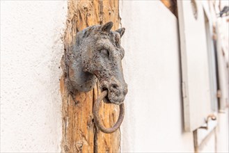 Old rustic horse head with a ring for driving horses in a backyard. Colmar