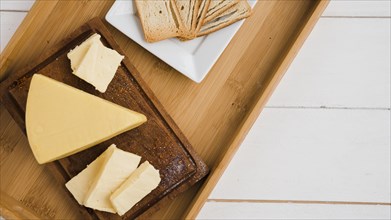 Triangular cheese wedges wooden tray against white desk