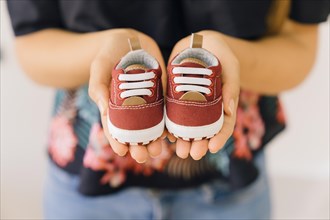 Newborn concept with woman with little shoes hands