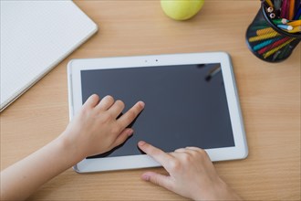 Crop child touching tablet
