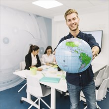 Happy young businessman holding globe office