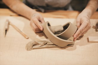 Female s hand making creative product with clay wooden desk