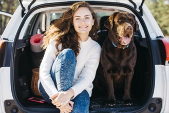 Woman sitting with her dog open trunk