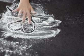 Close up girl s hand drawing heartshape flour