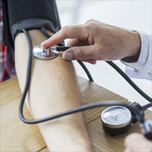 Crop hand with stethoscope measuring blood pressure