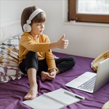 Boy sitting bed learning thumbs up