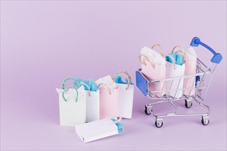 Many colorful paper shopping bags cart pink background