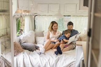 Long shot family looking through map caravan
