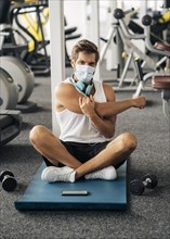Man with headphones medical mask gym working out mat