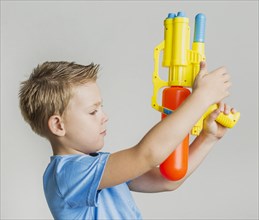 Adorable young boy playing with water gun