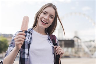 Portrait young happy woman holding popsicle amusement park