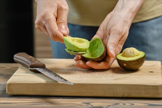 Closeup view of male hand removing avocado from skin with spoon