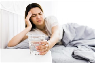 Female suffering from headache taking glass water