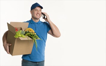 Happy delivery man talking phone holding grocery box