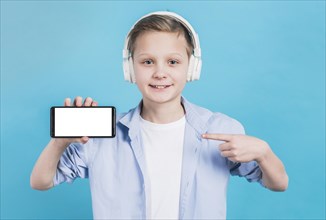Close up boy wearing headphone head pointing her finger toward mobile phone with blank screen