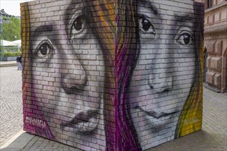 Graffiti of two huge woman's heads on a brick wall