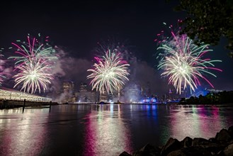 Independence day celebration in New York City with Macy's Fireworks in Lower Manhattan on East River and Brooklyn Bridge