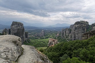 The monastery of Roussanou and behind it the monastery of Agios Nikolaos Anapafsas on sandstone rocks above the Pinios valley. The Greek Orthodox Meteora monasteries are built on sandstone cliffs abov...