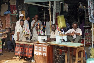Men behind old treadle sewing machines in sewing workshop in Omdurman