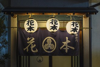Lanterns hanging outside the entrance of a traditional izakaya restaurant