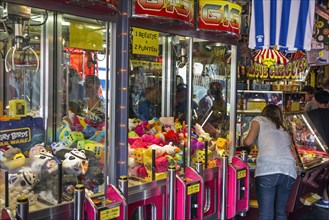 Arcade with claw crane game machines filled with toys and coin pusher