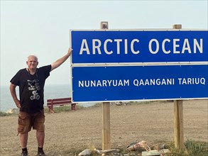 Tourist in front of sign Arctic Ocean