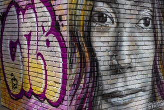 Graffiti of a giant woman's head on a brick wall