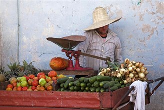 Cuban vendor selling fresh fruit and vegetables at market stall in Vinales