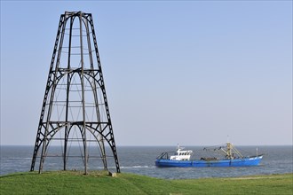 Cast iron beacon from 1854 and fishing boat sailing the Wadden Sea