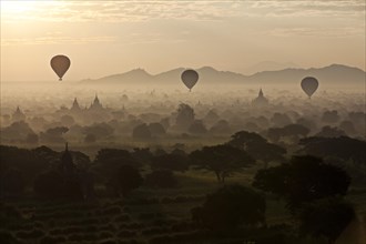 Hot air balloons over landscape with stupas