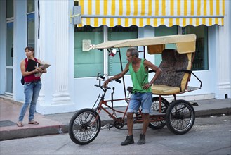 Man with three-wheeled bicycle taxi waiting for tourists in Cienfuegos