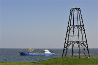 Cast iron beacon from 1854 and fishing boat sailing the Wadden Sea