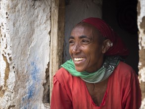Laughing woman in front of a mud hut