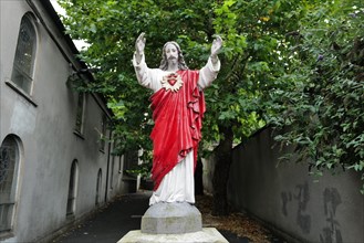 A red religious statue of Jesus with arms outstretched in a lane in Waterford city. Waterford