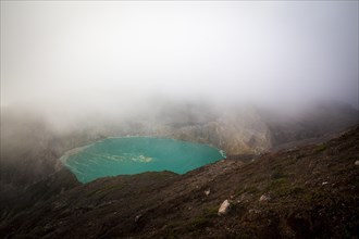 Fog over crater with turquoise crater lake