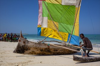 Outrigger boat on the beach with colourful sail