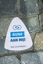 Sticker on pavement indicating to keep social distance of 1. 5 metres during 2020 COVID-19