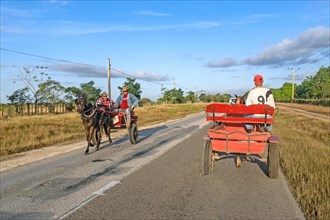 Cubans riding horse-drawn cart and carriage along the Carretera Central