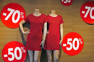 Discount notices showing deductions in shop window of clothes store during the summer sales in shopping street