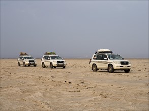 Tourists in off-road vehicles driving on salt desert